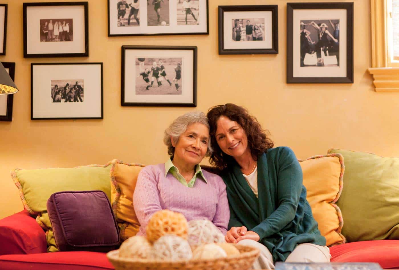 mother and daugther on couch with pictures on wall alzheimers