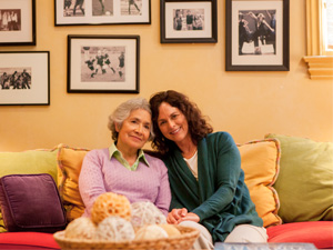 mother with alzheimer's sits beside daughter on couch