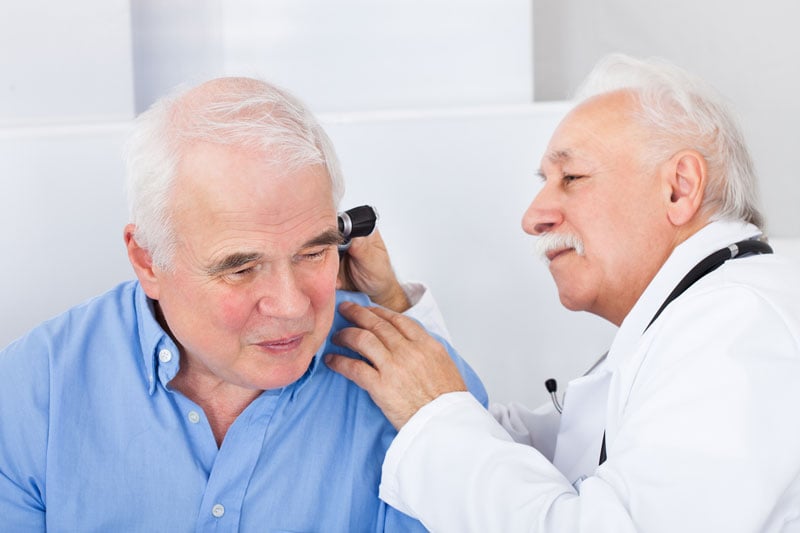 elderly women having hearing aid put on